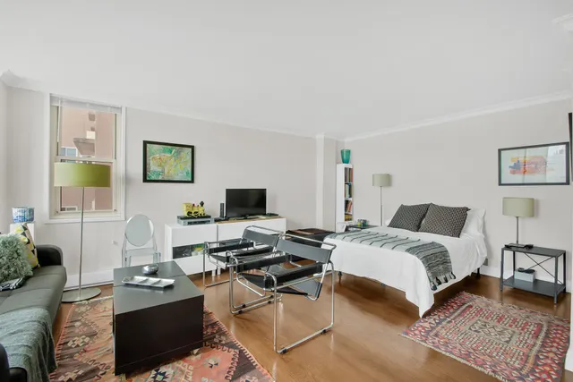 a bedroom with a bed and a computer on the desk next to a window