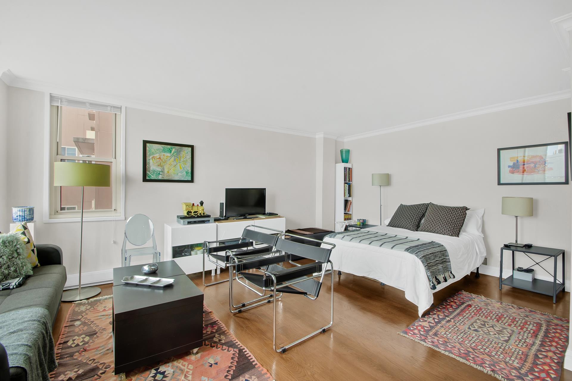 575 Main Street, Unit 1611 Manhattan, NY 10044 - Photo 3 of 9 a bedroom with a bed and a computer on the desk next to a window