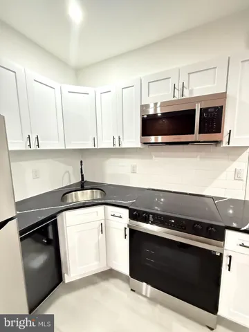 a kitchen with stainless steel appliances kitchen island granite countertop a refrigerator and a stove top oven