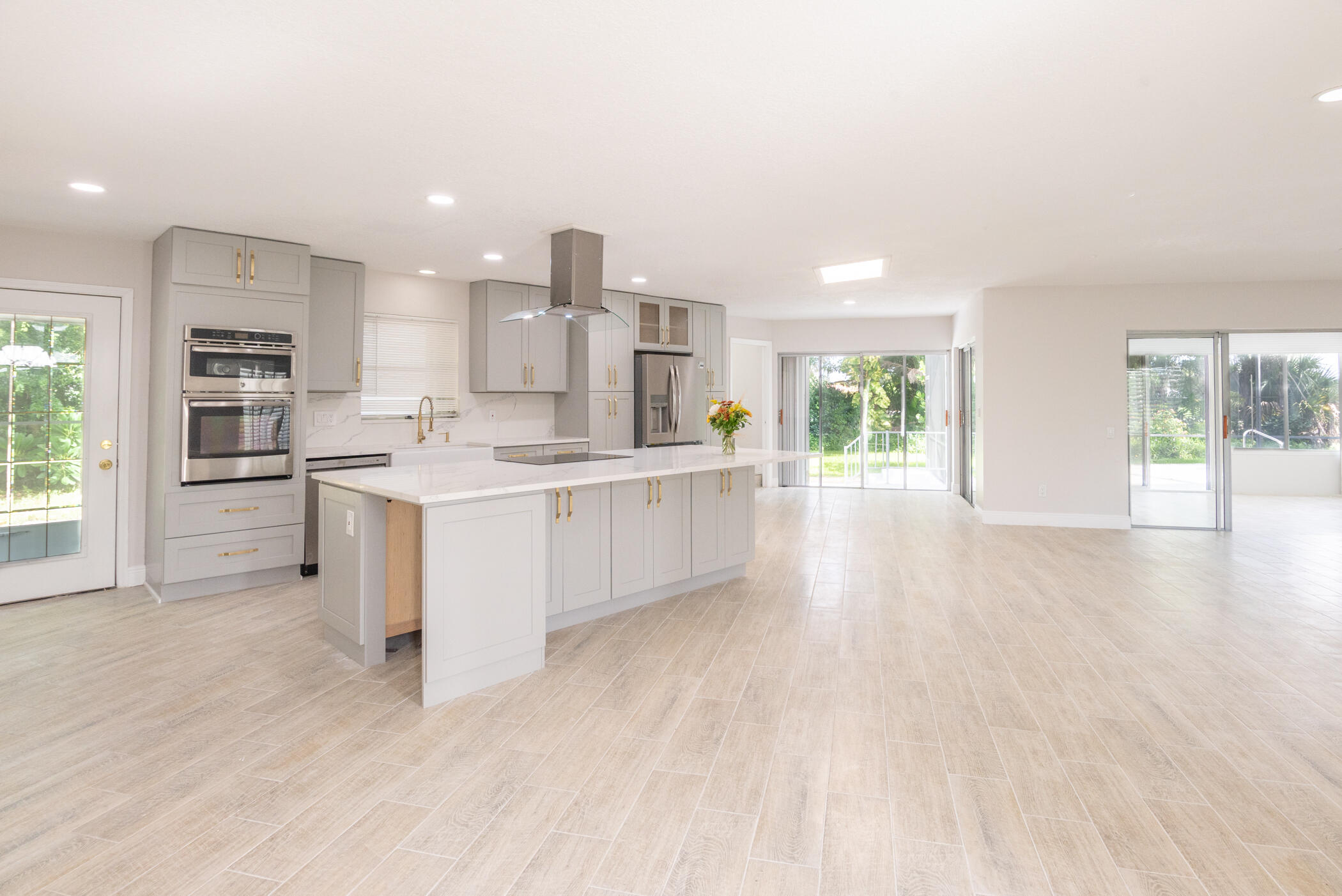 3441 Southeast Court Drive Stuart, FL 34997 - Photo 6 of 46 a large white kitchen with kitchen island white cabinets and wooden floor