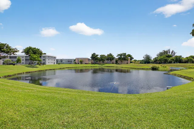 a view of a lake with a yard and large trees