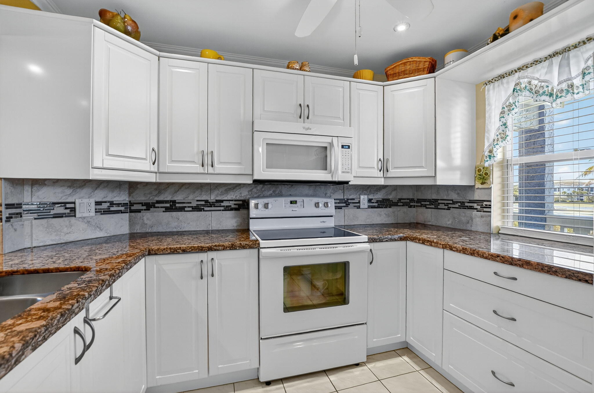 9880 Marina Boulevard, Unit 1522 Boca Raton, FL 33428 - Photo 3 of 52 a kitchen with granite countertop white cabinets and white appliances