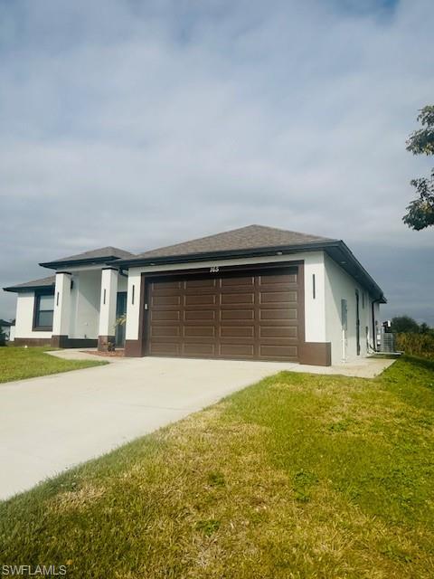 165 Patio Street Lehigh Acres, FL 33974 - Photo 3 of 34 View of front of house featuring stucco siding, concrete driveway, a front lawn, and a garage