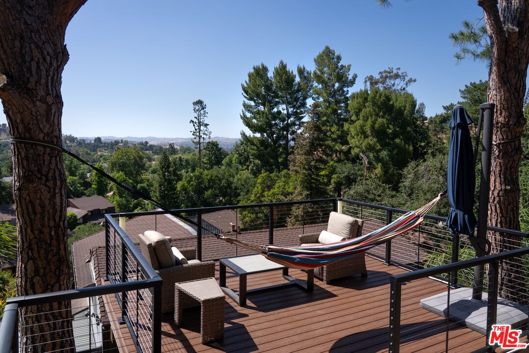4118 Oak Hollow Road Calabasas, CA 91302 - Photo 26 of 55 a view of a roof deck with table and chairs a barbeque with wooden fence and floor