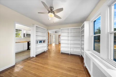 a view of an empty room with window and wooden floor