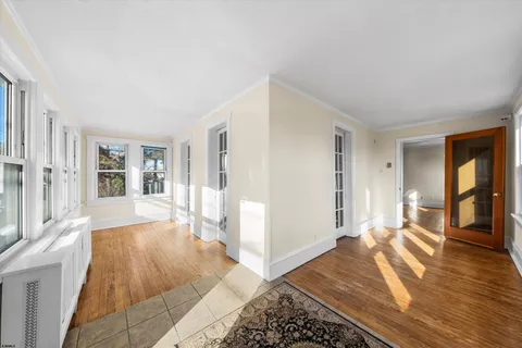 a view of an empty room with window and wooden floor