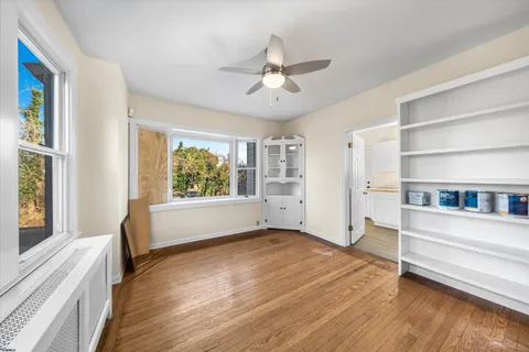 a view of an empty room with window and wooden floor