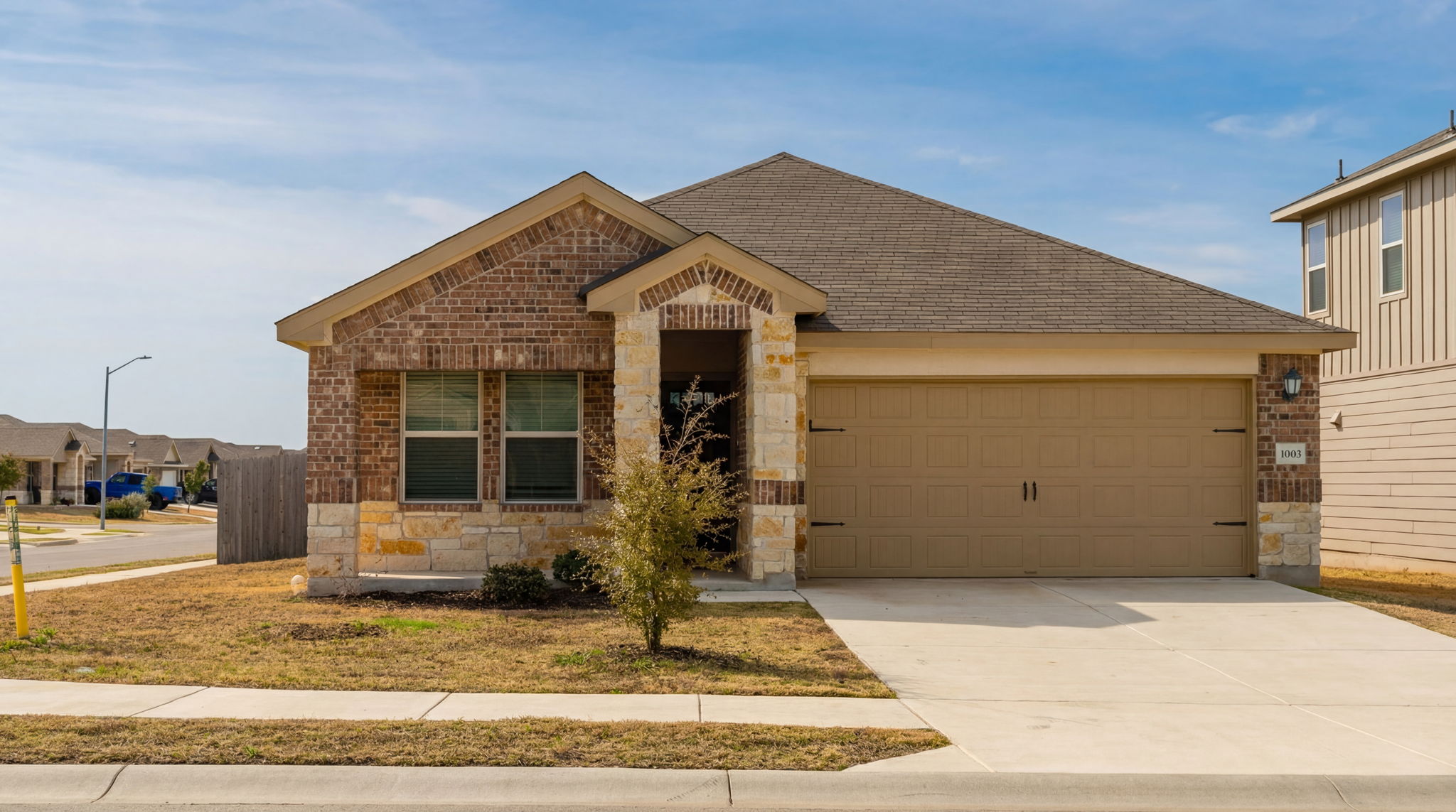 1003 Round Bale Road Hutto, TX 78634 - Photo 9 of 29 View of front of home with brick siding, concrete driveway, an attached garage, stone siding, and a shingled roof
