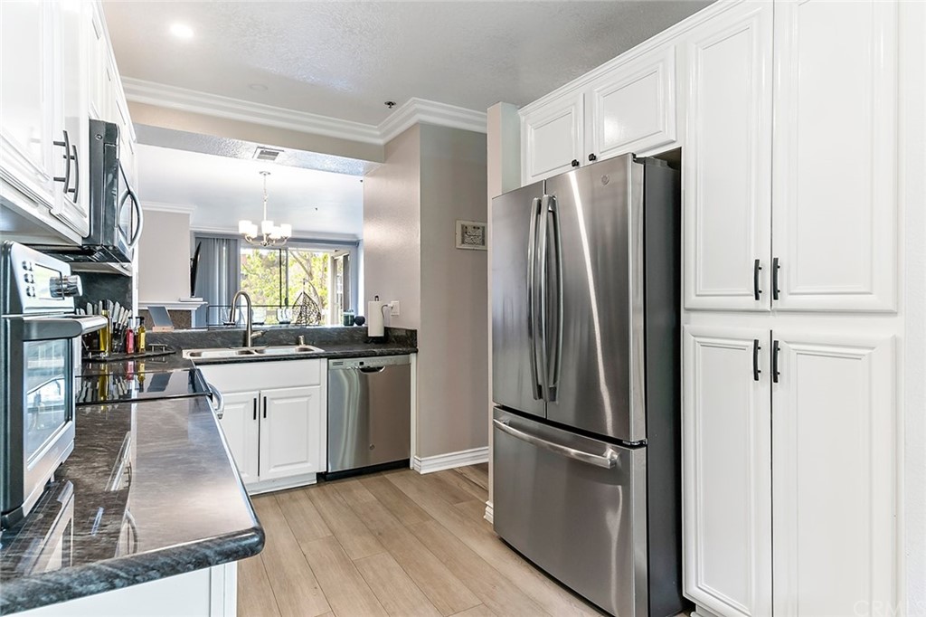 20301 Bluffside Circle, Unit 304 Huntington Beach, CA 92646 - Photo 11 of 40 a kitchen with stainless steel appliances a refrigerator a sink a stove and white cabinets