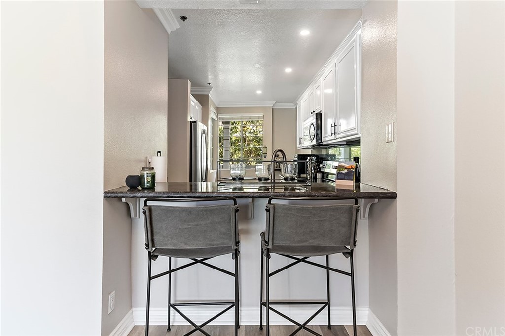20301 Bluffside Circle, Unit 304 Huntington Beach, CA 92646 - Photo 17 of 40 a kitchen with stainless steel appliances a dining table chairs and a refrigerator