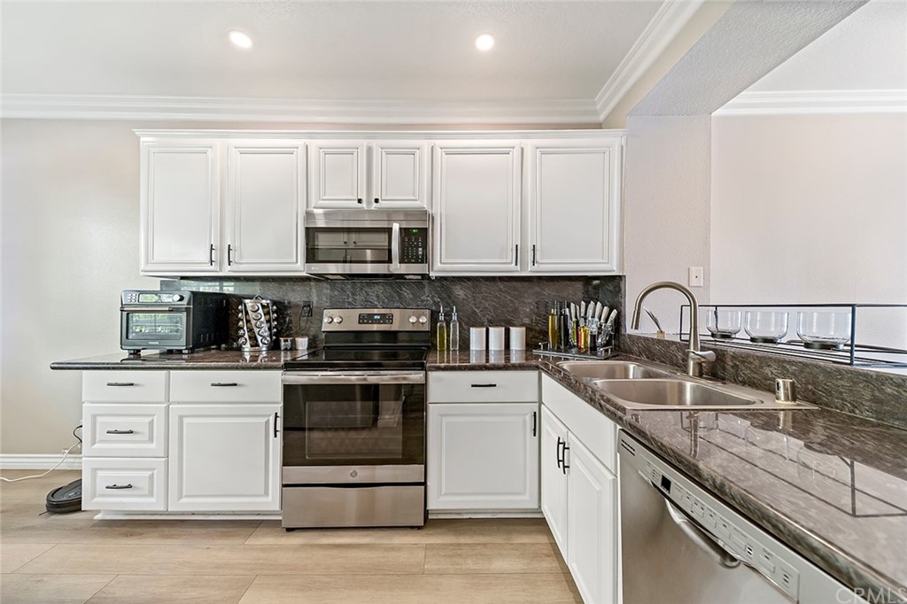 20301 Bluffside Circle, Unit 304 Huntington Beach, CA 92646 - Photo 5 of 40 a kitchen with stainless steel appliances granite countertop a stove a sink and a microwave
