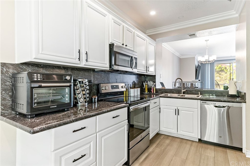 20301 Bluffside Circle, Unit 304 Huntington Beach, CA 92646 - Photo 6 of 40 a kitchen with stainless steel appliances granite countertop a stove a sink and a microwave
