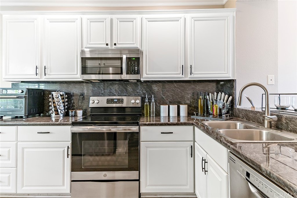 20301 Bluffside Circle, Unit 304 Huntington Beach, CA 92646 - Photo 8 of 40 a kitchen with granite countertop white cabinets and stainless steel appliances