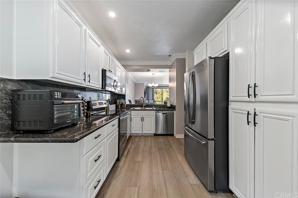 20301 Bluffside Circle, Unit 304 Huntington Beach, CA 92646 - Photo 10 of 40 a kitchen with stainless steel appliances granite countertop a refrigerator a stove and a sink