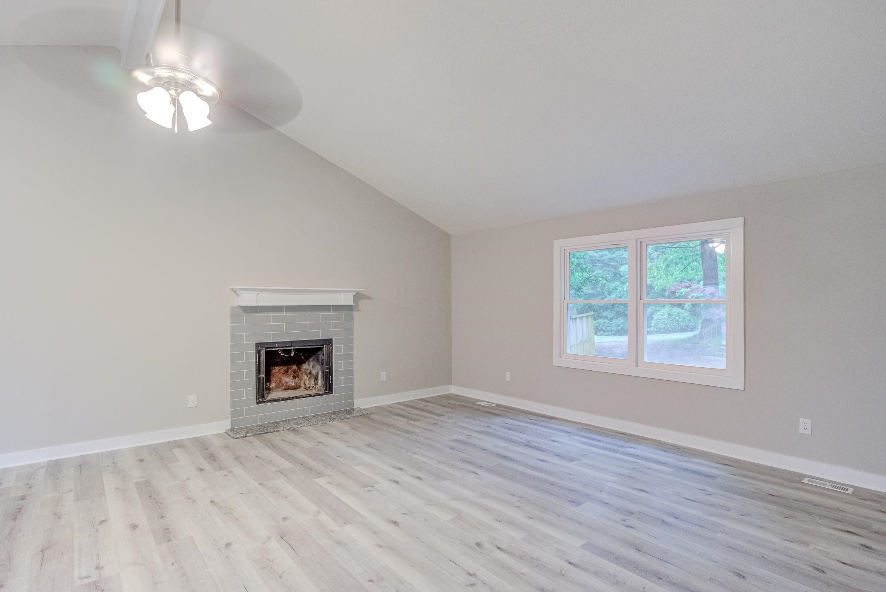 5404 Pear Orchard Lane Raleigh, NC 27616 - Photo 3 of 22 an empty room with wooden floor a chandelier fan and windows