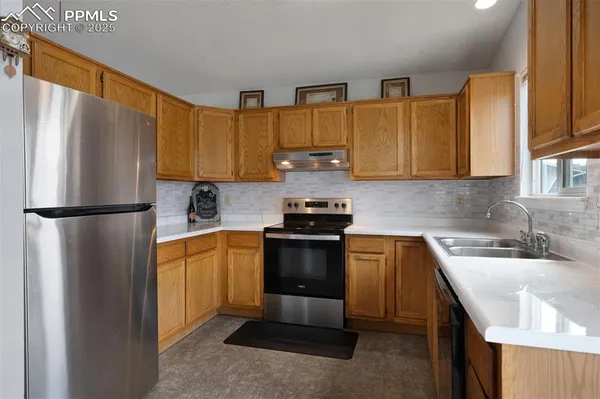 a kitchen with stainless steel appliances granite countertop a refrigerator sink and stove