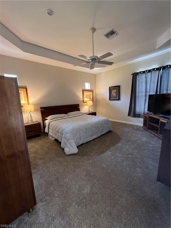 7896 Founders Circle Naples, FL 34104 - Photo 10 of 18 a bedroom with a bed a chandelier and flat screen tv