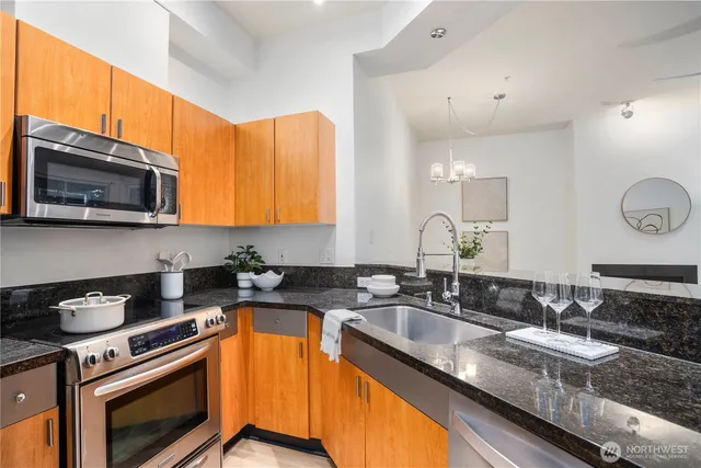 a kitchen with granite countertop a sink a stove a microwave and wooden cabinets