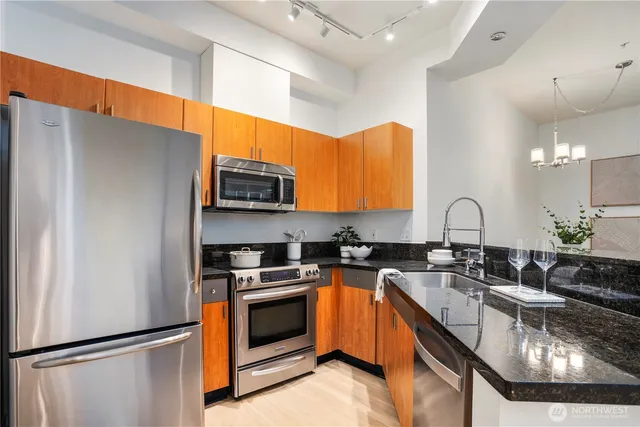 a kitchen with stainless steel appliances granite countertop a sink a stove and a refrigerator
