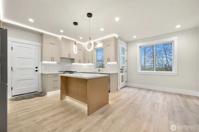 a large kitchen with granite countertop a large counter top a sink stainless steel appliances and cabinets