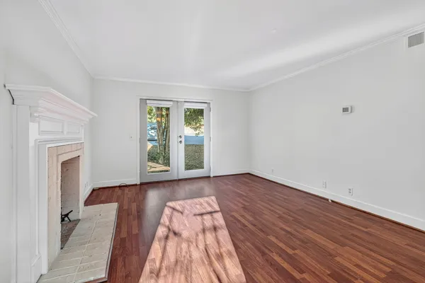 a view of an empty room with wooden floor and a window
