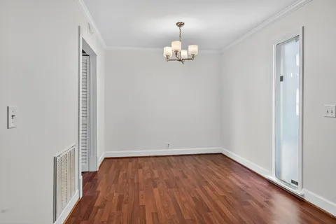 an empty room with wooden floor and chandelier