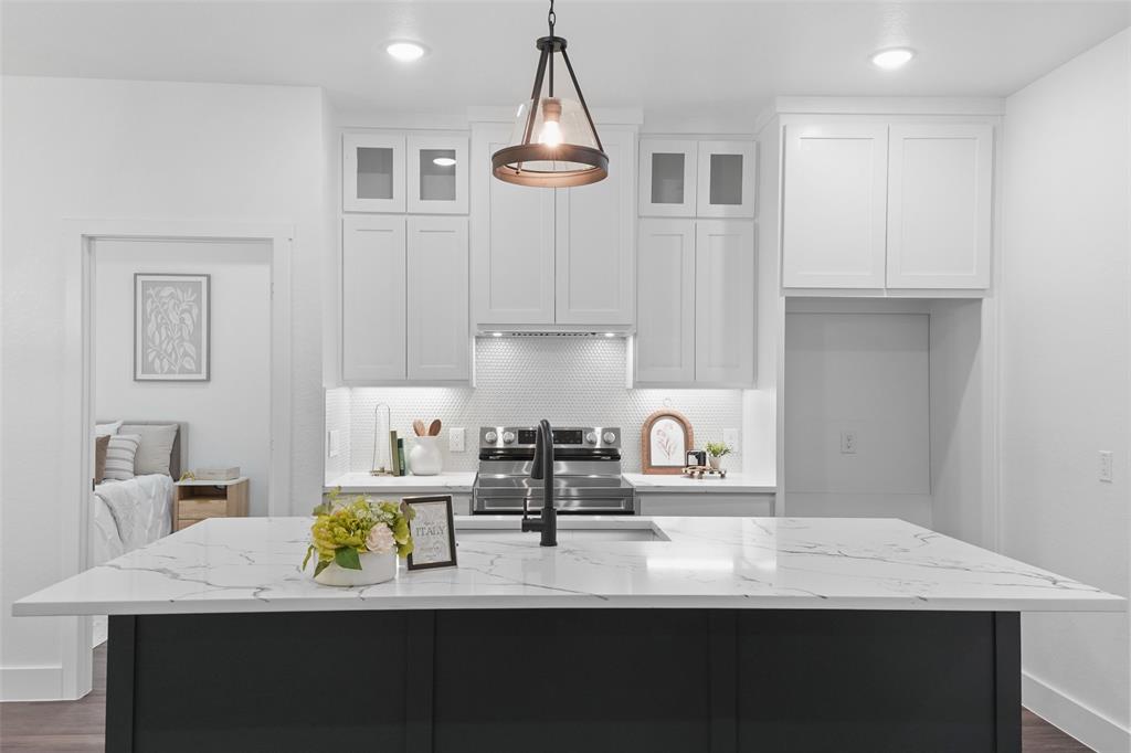 122 East Beachwood Loop Trinidad, TX 75163 - Photo 14 of 35 Spacious kitchen featuring a large island with a stone-finish countertop, white upper cabinetry with glass-front accents, dark lower cabinetry, and recessed lighting