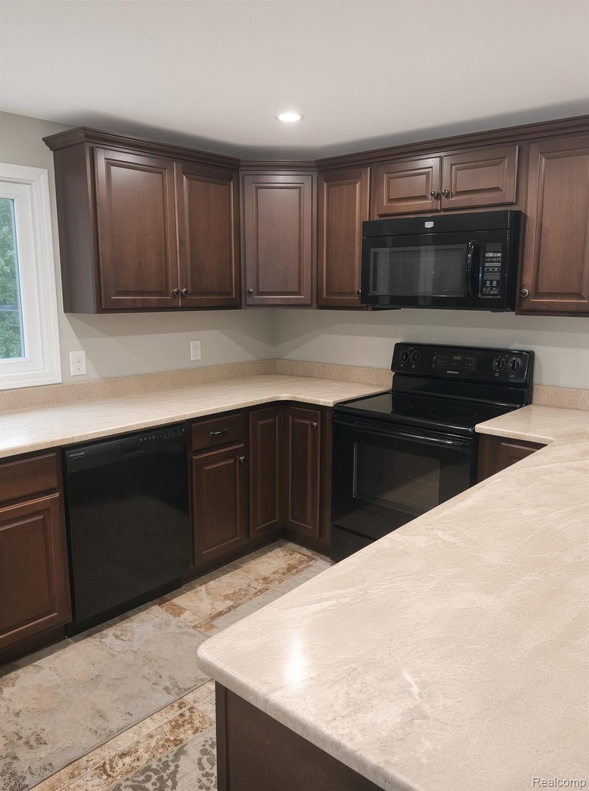 8922 Stone Road Algonac, MI 48001 - Photo 3 of 15 Kitchen featuring wood cabinetry, light-toned countertops, a built-in microwave, and a black range