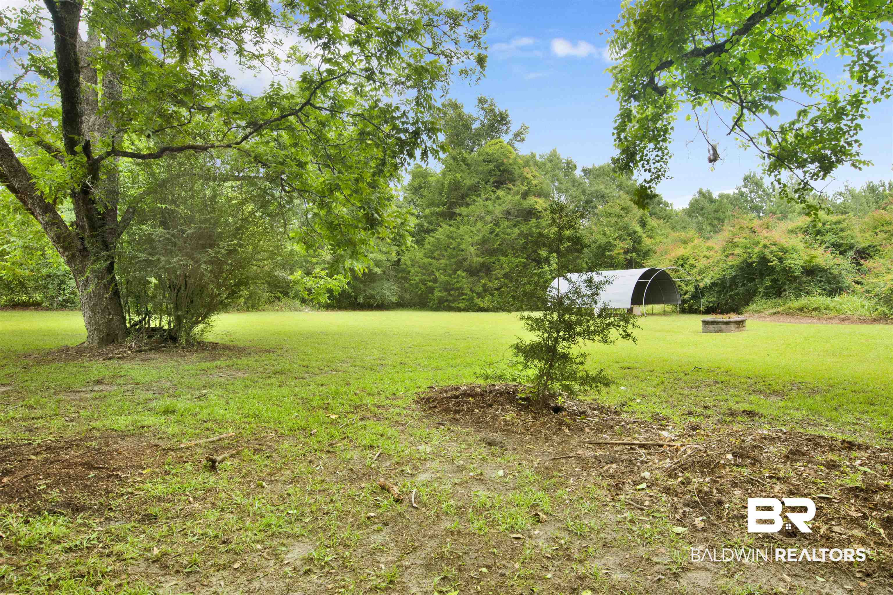 17714 Horseneck Road Bay Minette, AL 36507 - Photo 31 of 36 Expansive green space featuring a large mature tree, a smaller established tree, a dense shrub, and a metal quonset hut structure