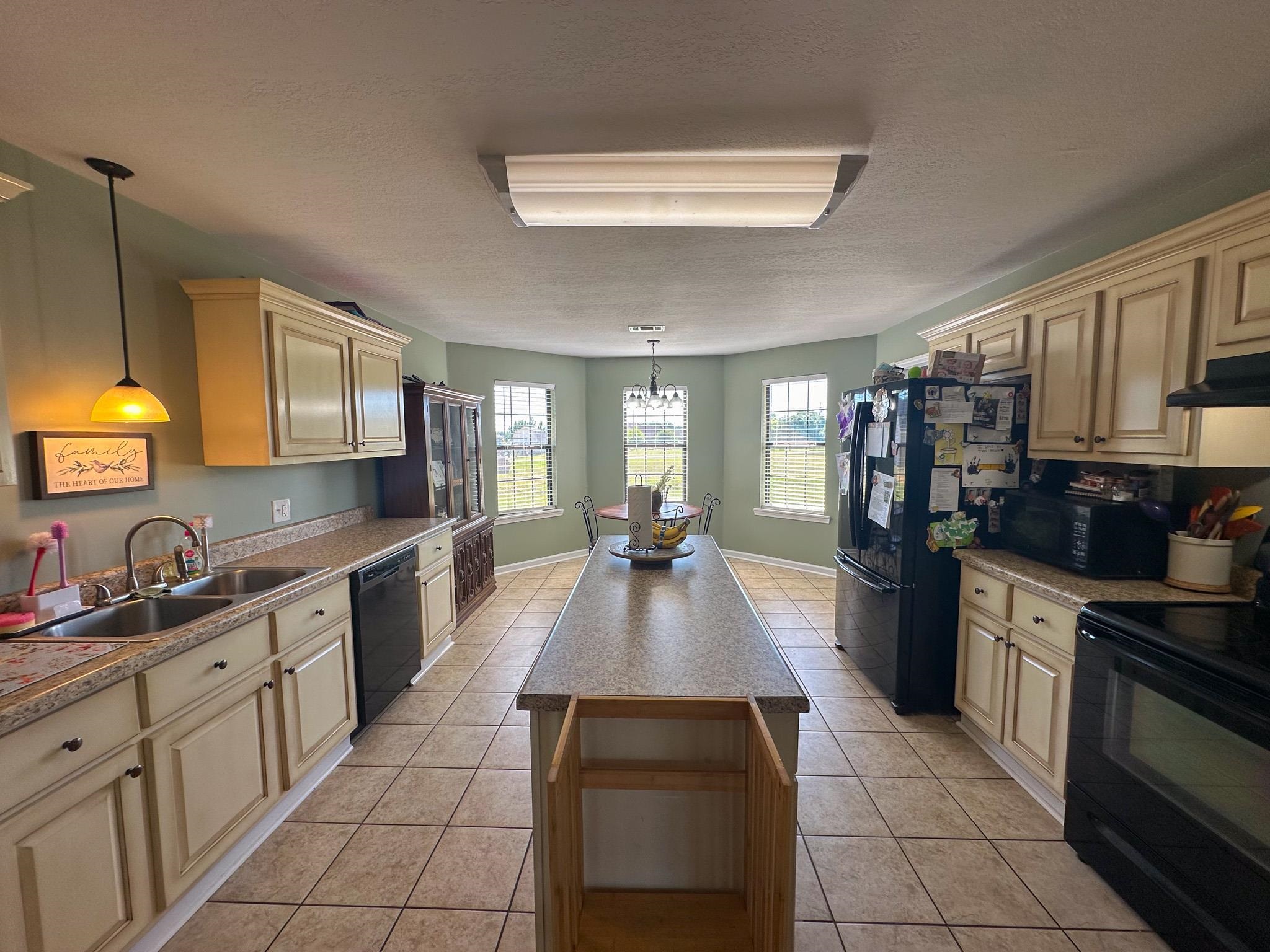 2 Raptor Drive Belmont, MS 38827 - Photo 5 of 18 Kitchen with cream cabinetry, black appliances, wall chimney exhaust hood, decorative light fixtures, and sink