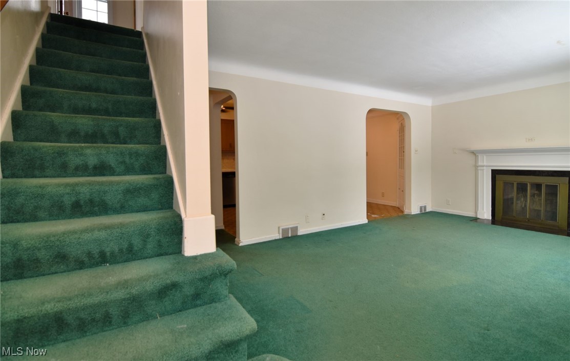 6308 Highland Road Cleveland, OH 44143 - Photo 6 of 40 Stairway with a fireplace with flush hearth, arched walkways, visible vents, and carpet