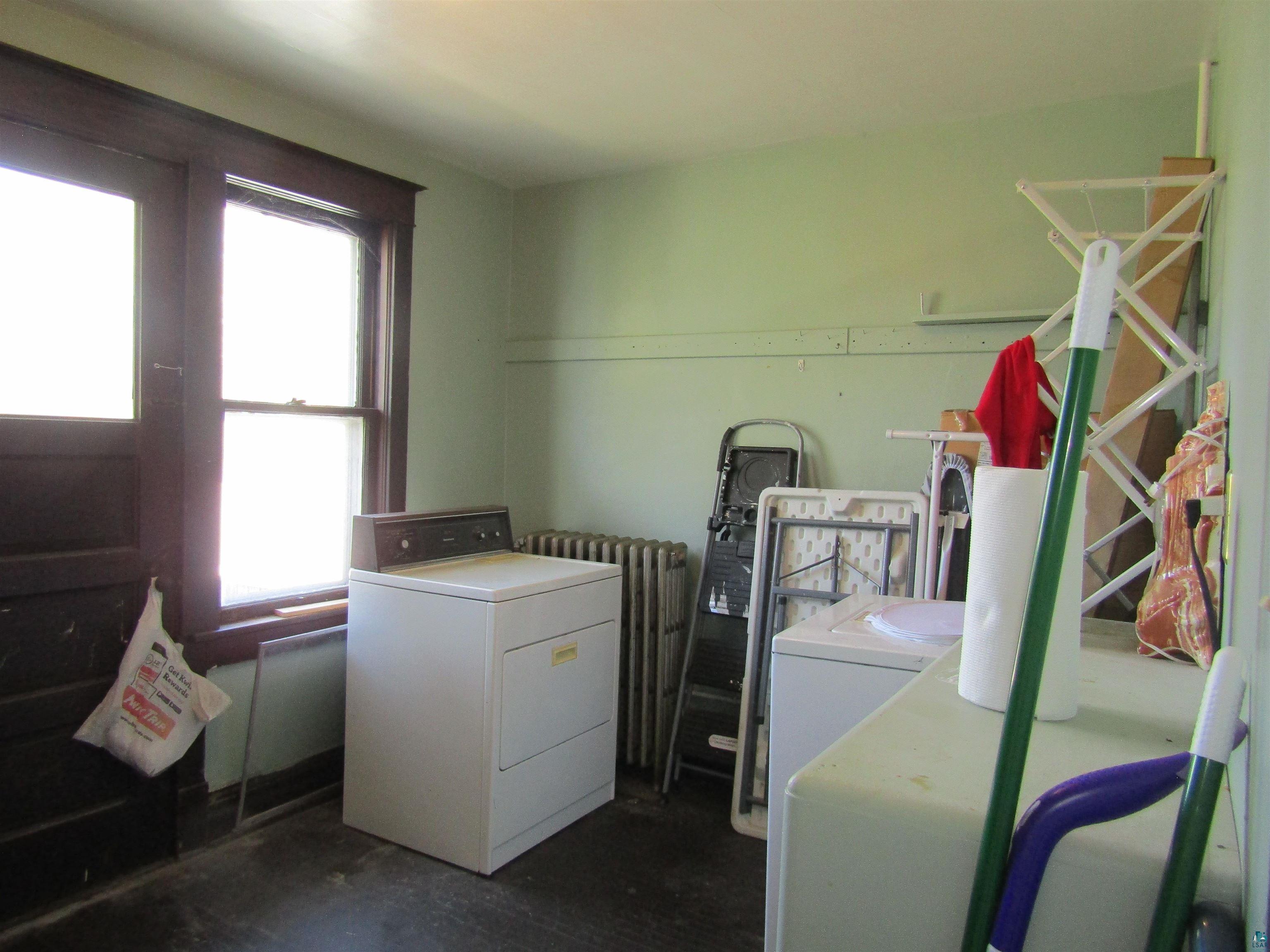 1115 Harrison Street Superior, WI 54880 - Photo 42 of 49 Laundry area featuring a side-by-side washer and dryer, wood-finish flooring, and a window with dark wood trim
