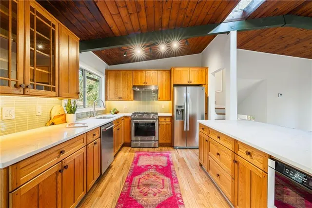 a large kitchen with stainless steel appliances kitchen island granite countertop a sink and dishwasher a stove with wooden floor