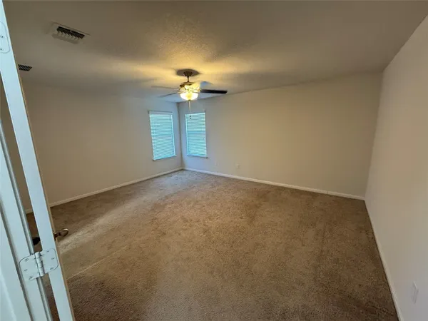 an empty room with a chandelier fan and a window