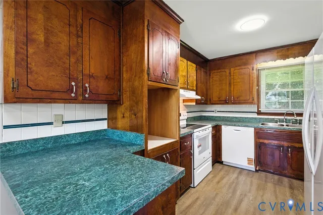 a kitchen with stainless steel appliances granite countertop a refrigerator a stove top oven and a sink with wooden cabinets