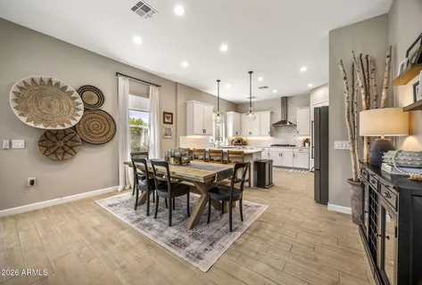 a dining room with stainless steel appliances granite countertop a stove top oven a refrigerator a dining table and chairs with wooden floor