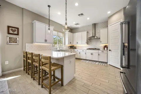 a kitchen with stainless steel appliances granite countertop a sink a stove a refrigerator and island with wooden floor