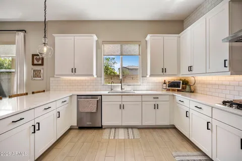 a kitchen with granite countertop white cabinets white appliances a sink and a window