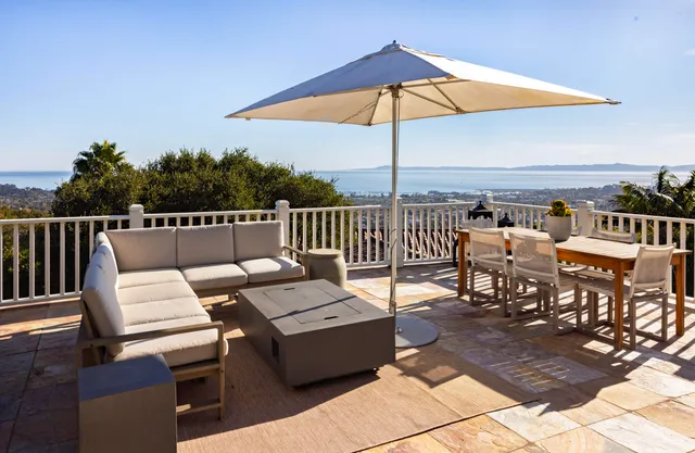 an outdoor sitting area with furniture and umbrella