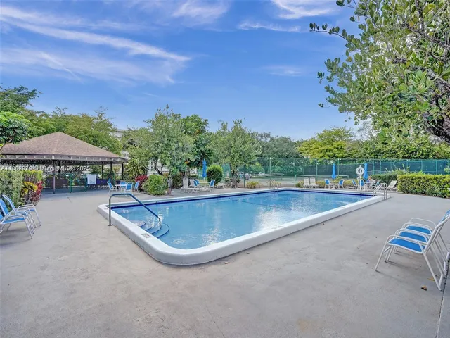 a view of a swimming pool and lounge chairs in back yard