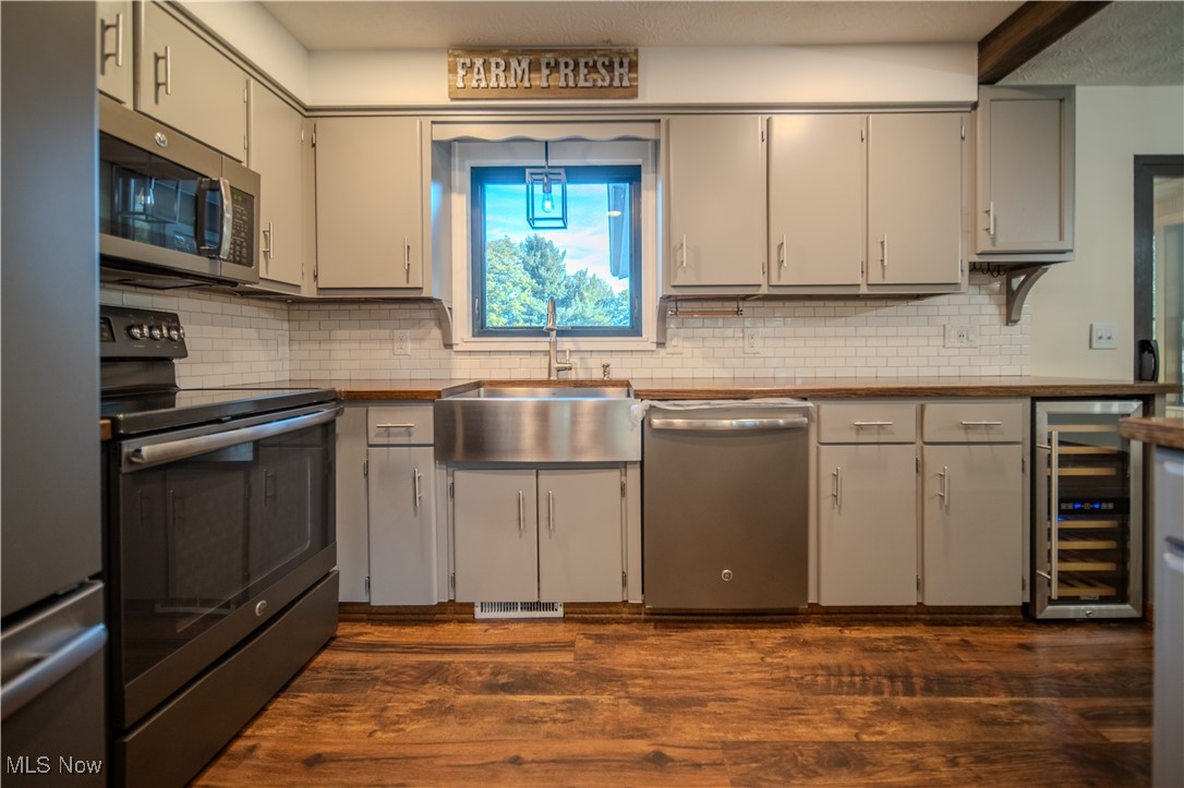 3459 Laubert Road Atwater, OH 44201 - Photo 13 of 39 Kitchen with stainless steel appliances, dark wood-style floors, wine cooler, and decorative backsplash