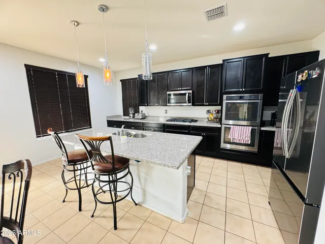 a kitchen with stainless steel appliances kitchen island granite countertop a refrigerator and a stove top oven