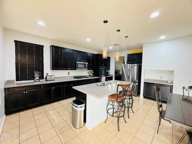 a kitchen with stainless steel appliances kitchen island granite countertop a sink a stove a dining table and chairs