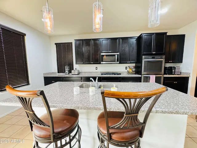 a kitchen with stainless steel appliances kitchen island granite countertop a kitchen island a blue chairs and wooden cabinets