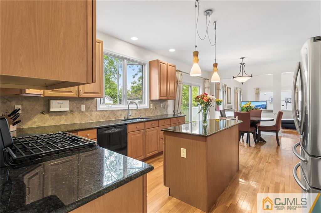 104 Mundy Avenue Edison, NJ 08820 - Photo 12 of 55 a kitchen with stainless steel appliances granite countertop a stove a sink dishwasher and a dining table with wooden floor