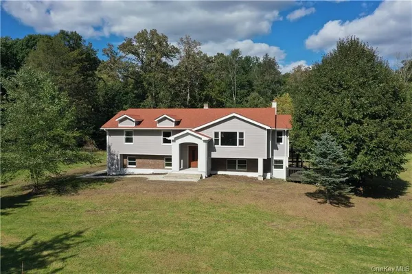 a view of a white house with a big yard and large trees