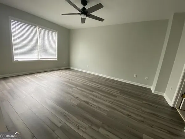 an empty room with wooden floor fan and windows