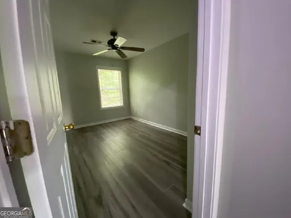 a view of empty room with wooden floor and fan