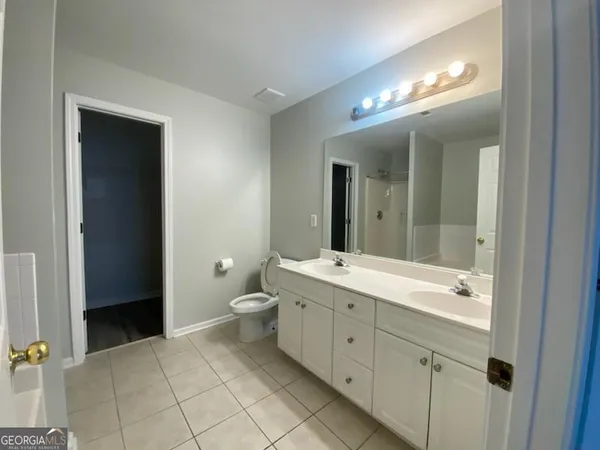a spacious bathroom with a double vanity sink a toilet and a mirror