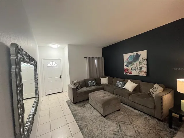 a living room with furniture and a refrigerator